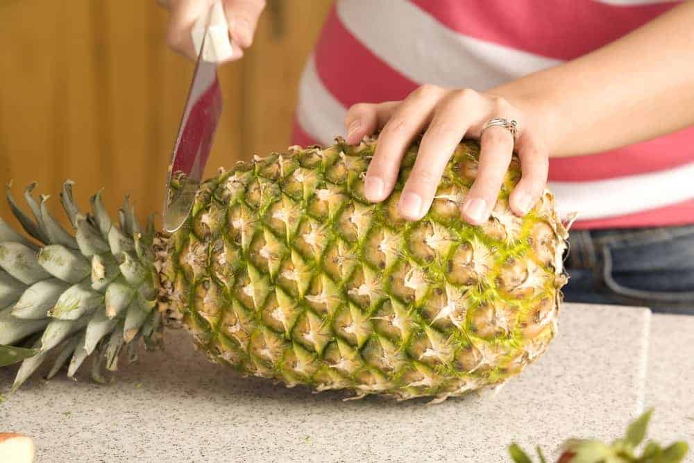 Woman cutting pineapple close up