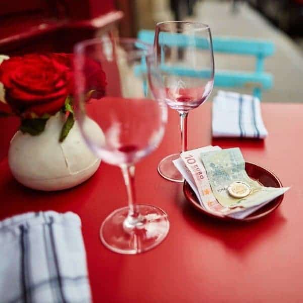 Two empty wine glasses with bills and coins