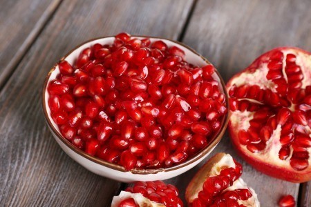 Beautiful composition with juicy pomegranate seeds, on old wooden table
