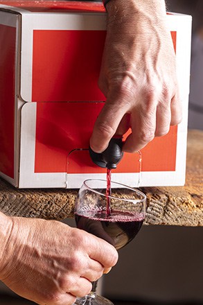 pouring red wine from a box